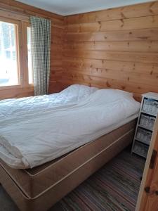 a bed in a room with a wooden wall at Jamali Cabin in Lieksa