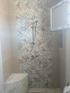 a bathroom with a shower with a tile wall at Family corner in Ḩammām al Ghazzāz