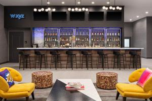 a bar with yellow chairs and a table andools at Aloft Katy Mills in Katy