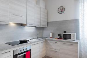eine Küche mit weißen Schränken, einer Spüle und einer Mikrowelle in der Unterkunft Casa Viotti Monza in Monza