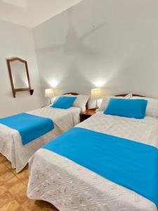 two beds in a room with blue and white at Hotel Firenze in Tarapoto