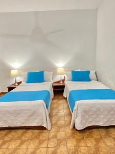dwa łóżka w pokoju niebiesko-białym w obiekcie Hotel Firenze w mieście Tarapoto