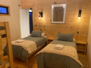 two beds in a room with wooden walls at Piedra Nevada in Malalcahuello