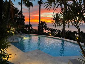 a swimming pool with a sunset in the background at Residence AU 'TI SUCRIER in Deshaies