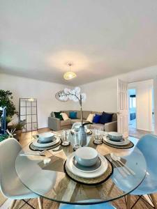 a dining room with a glass table and blue chairs at BEAUTIFUL WINDSOR 2 BED, PERFECT LOCATION, 5 Mins Walk to Centre, Private Gated Parking, Legoland, Ascot in Windsor