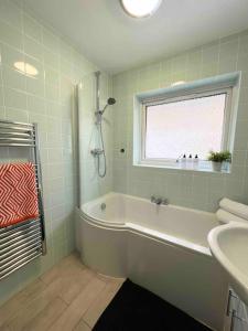 a bathroom with a tub and a window and a sink at BEAUTIFUL WINDSOR 2 BED, PERFECT LOCATION, 5 Mins Walk to Centre, Private Gated Parking, Legoland, Ascot in Windsor