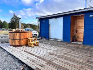 un edificio azul con terraza de madera y bañera de hidromasaje en Casa Leon, en Puerto Varas