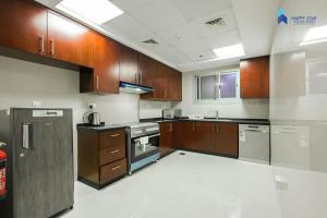 a large kitchen with wooden cabinets and stainless steel appliances at 2 BR Perfect for Family/Groups near MOE in Dubai