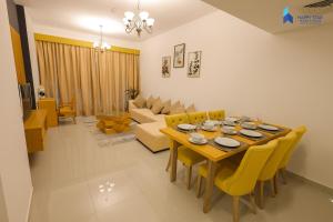 a dining room with a table and yellow chairs at 2 BR Perfect for Family/Groups near MOE in Dubai