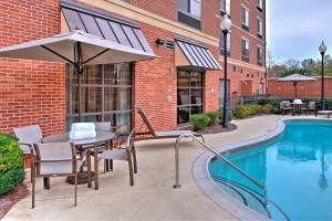 a patio with a table and an umbrella next to a pool at Courtyard Clemson in Clemson