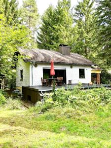 een wit huis met een tafel en een rode paraplu bij Haus mit Sauna am Waldrand - Nähe Brombachsee Altmühlsee in Windsbach
