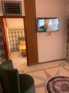 Pokój z telewizorem na ścianie i krzesłem w obiekcie Appartement near to AirPort 262 avenue el khalij w Marakeszu
