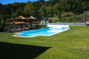 una piscina en un patio con sillas y sombrillas en Villa Ramiro en Celorico de Basto