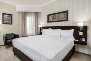 um quarto de hotel com uma cama grande e uma cadeira em Copantl Hotel & Convention Center em San Pedro Sula