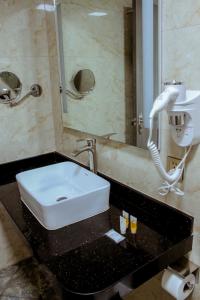ein Badezimmer mit einem Waschbecken und einem Telefon auf der Theke in der Unterkunft Gold Source Hotel in Lima