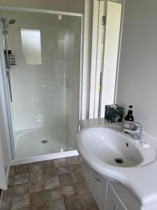 a white bathroom with a shower and a sink at Ocean Air Carters Beach in Carters Beach