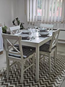 uma mesa de jantar branca com cadeiras e copos de vinho em Epicentar apartment em Loznica