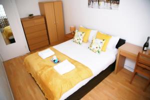 a bedroom with a large white bed with yellow sheets at Kenton Cozy Apartment in Harrow