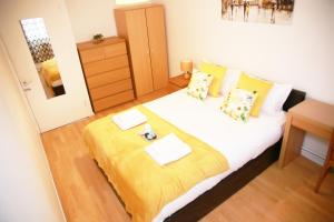 a bedroom with a large bed with a yellow blanket at Kenton Cozy Apartment in Harrow