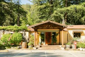 a small yellow house with a porch with plants at Fernwood Resort in Big Sur