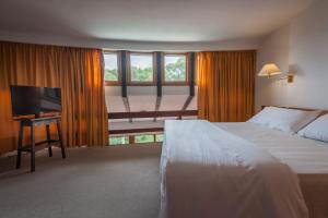 a hotel room with a bed and a flat screen tv at Hotel del Bosque in Pinamar