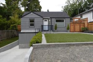 a small grey house with a fence and a yard at Cozy Crown Hill Carkeek Cottage w/3 Beds, Full Kitchen & Backyard in North Seattle in Seattle