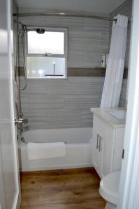 a bathroom with a tub and a toilet and a window at Cozy Crown Hill Carkeek Cottage w/3 Beds, Full Kitchen & Backyard in North Seattle in Seattle