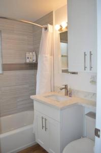 a white bathroom with a sink and a bath tub at Cozy Crown Hill Carkeek Cottage w/3 Beds, Full Kitchen & Backyard in North Seattle in Seattle