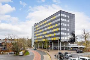 a tall building with cars parked in a parking lot at Fully Furnished City Centre 2Bed 2Bath Apartment with Parking Rooftop Terrace Communal Lounge 10 mins to Ascot Racecourse Legoland Pets are allowed in Bracknell