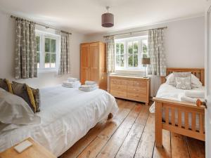 a bedroom with two beds and a dresser and two windows at Chittering Farm in Stretham