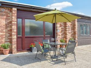 een tafel en stoelen met een gele paraplu bij Serendipity in Ferndown