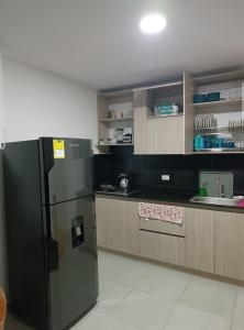 uma cozinha com um frigorífico preto e armários de madeira em Apartamento 201 Palmar de los vientos em San Bernardo del Viento