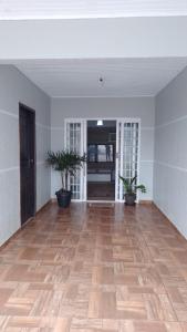 an empty room with two potted plants on a wooden floor at Casa Gil in Foz do Iguaçu