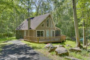 una casa verde con porche en el bosque en Bushkill Mountain Getaway with Community Amenities, en Sandyville