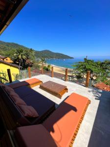 a patio with lounge chairs and the ocean in the background at La Coquille in Praia de Araçatiba