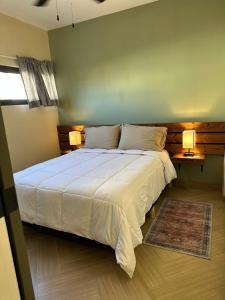 um quarto com uma grande cama branca e 2 candeeiros em Habitación 23 - Green Casitas em Ensenada