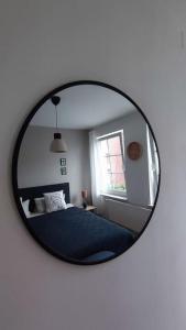 ein Spiegel, der ein Schlafzimmer mit einem Bett und einem Fenster reflektiert in der Unterkunft Ein Haus für sich in Lübeck