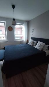 1 Schlafzimmer mit einem schwarzen Bett und 2 Fenstern in der Unterkunft Ein Haus für sich in Lübeck