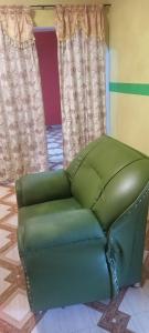 a green couch sitting in a room with curtains at Executive Lodge in Kasoa