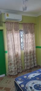 a room with a bed and a window with curtains at Executive Lodge in Kasoa