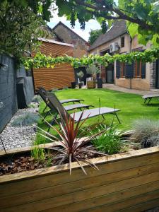 un jardin avec un banc et des tables dans une cour dans l'établissement ChezSonBernois :), à Venizy