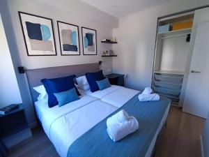 una camera da letto con un grande letto bianco con cuscini blu di RAMBLA DREAMS Nuevo apartamento céntrico y 1GB a Santa Cruz de Tenerife