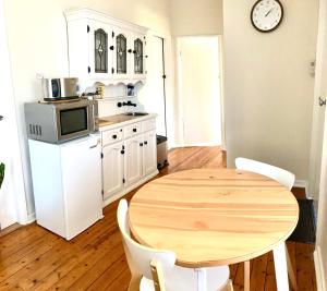 a kitchen with a wooden table and a microwave at Rose End Cozy Apartment in Tumut