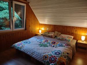 a bed in a wooden room with two windows at Chata v objetí hor: výborná dostupnost a soukromí in Párnica