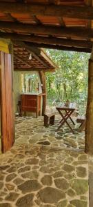 patio al aire libre con mesa y suelo de piedra en Chalé O Canto dos Pássaro, en Paraty