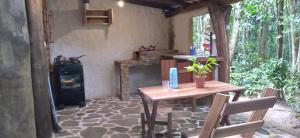 un patio con mesa de madera y estufa de leña en Chalé O Canto dos Pássaro en Paraty