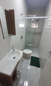 uma casa de banho branca com um lavatório e um WC em Casa com piscina - Praia do Pernambuco no Guarujá