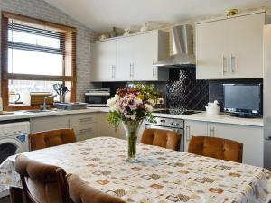 una cocina con una mesa con un jarrón de flores. en Old Stable Cottage en Uplawmoor