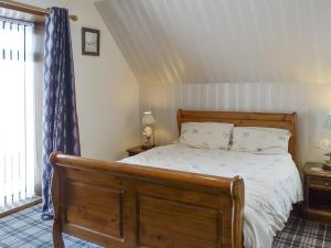 a bedroom with a bed with a wooden bed frame at Old Stable Cottage in Uplawmoor