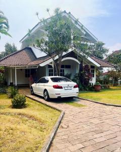 Villa Dedaun Batu في باتو: سيارة بيضاء متوقفة أمام منزل